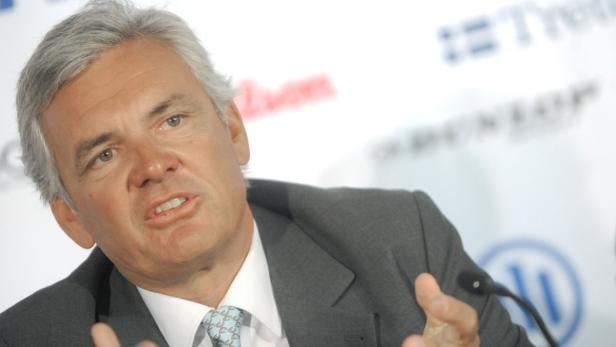 Ein Mann in einem grauen Anzug spricht vor einem Mikrofon.