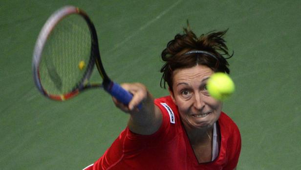 Eine Tennisspielerin schlägt einen gelben Tennisball mit ihrem Schläger.