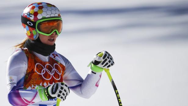 Eine Skirennläuferin mit Helm und Skibrille vor einer verschneiten Landschaft.