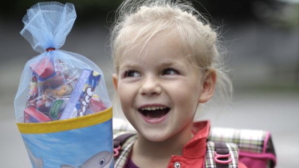 Ein lachendes Mädchen mit Schultüte und Schulranzen.