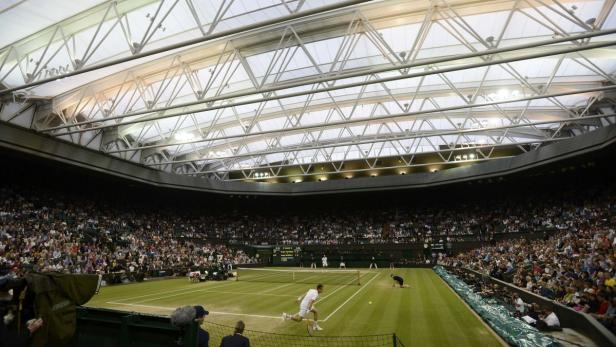 Ein Tennisspieler beim Aufschlag auf dem Centre Court in Wimbledon vor vollen Zuschauerrängen.