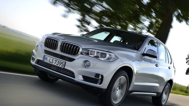 Ein silberner BMW X5 fährt auf einer Landstraße.