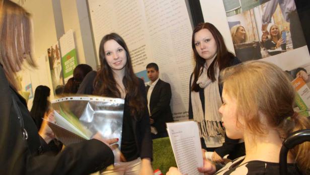 Mehrere Personen stehen vor Plakaten und lesen Dokumente.