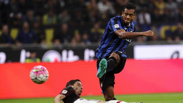 Ein Fußballspieler tritt im Spiel gegen einen am Boden liegenden Gegner gegen den Ball.