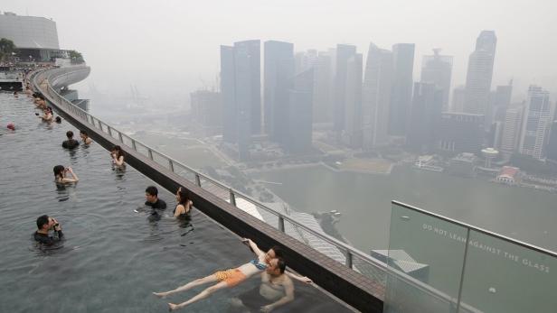 People swim in an infinity pool overlooking the sk In Singapur sieht es derzeit recht düster aus.