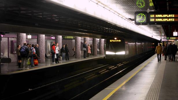 Menschen warten auf die U-Bahn am Bahnsteig der Station Karlsplatz in Wien.
