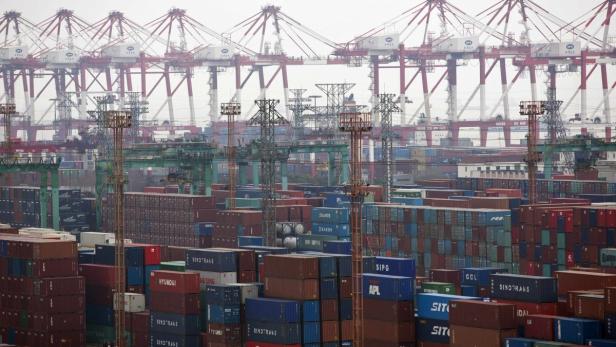 Ein Containerhafen mit vielen Containern und Kränen im Hintergrund.