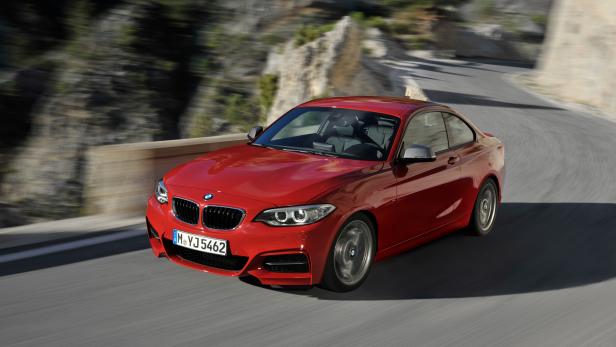 Ein roter BMW fährt auf einer kurvenreichen Straße entlang.