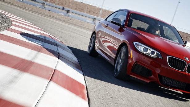 Ein roter BMW fährt auf einer Rennstrecke.