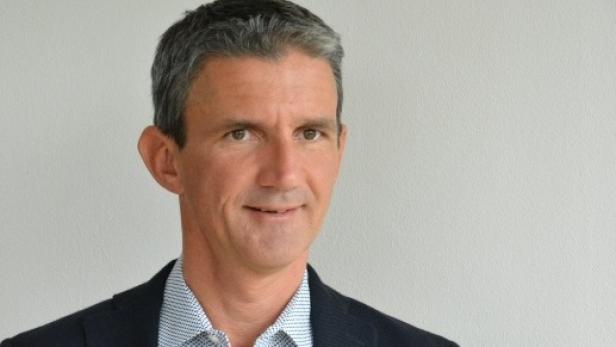 Porträt eines Mannes mit grau meliertem Haar und einem dunklen Sakko.