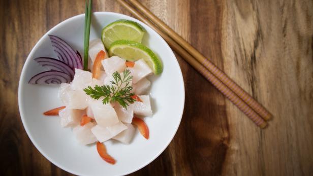 Traditional Ceviche bowl with white fish. Top view on wooden background.