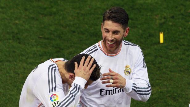 Sergio Ramos lacht, während ein anderer Fußballspieler den Kopf in den Händen hält.