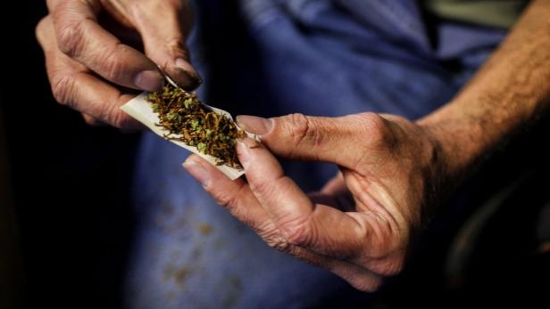 Ein Mann rollt eine Zigarette mit Tabak und Marihuana.