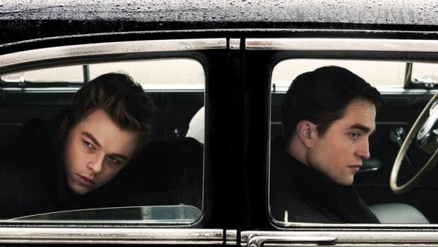 Zwei Männer, vermutlich Schauspieler, sitzen in einem Oldtimer.