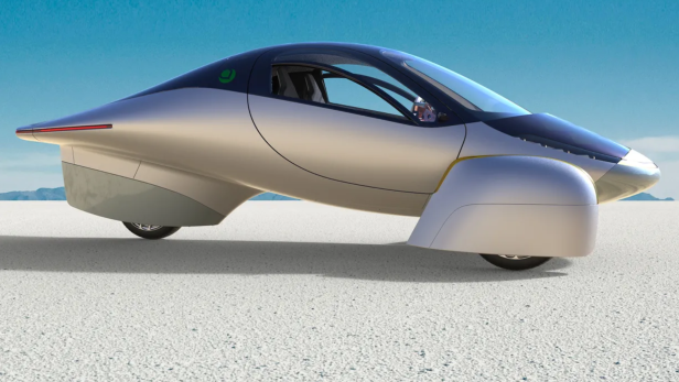 Ein silberfarbenes, futuristisches Auto steht in einer Wüstenlandschaft.