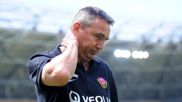 Ein Mann im Dynamo Dresden Polohemd greift sich an den Nacken.