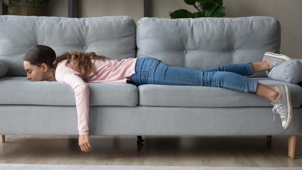 Young woman lying buried her face in sofa feels tired