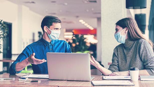 business colleagues in protective masks sitting at the office Desk