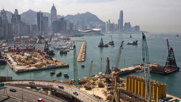Blick auf Bauarbeiten im Hafen von Hongkong vor der Skyline der Stadt.