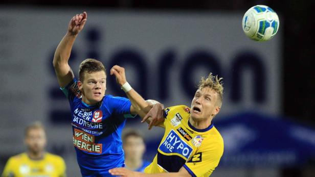 Zwei Fußballspieler kämpfen um den Ball während eines Spiels.