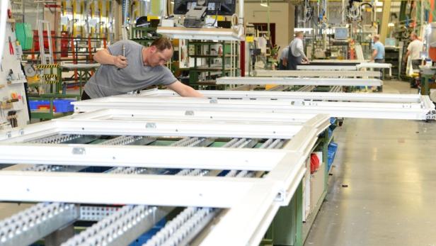 Ein Arbeiter montiert Fensterrahmen in einer Fabrikhalle.