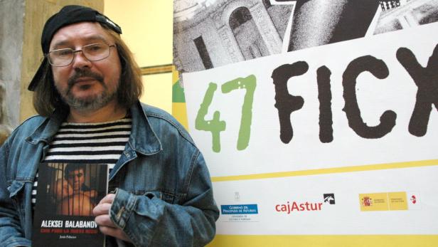 Ein Mann mit Brille hält ein Buch über Aleksei Balabanov vor einem „47 FICX“-Poster.
