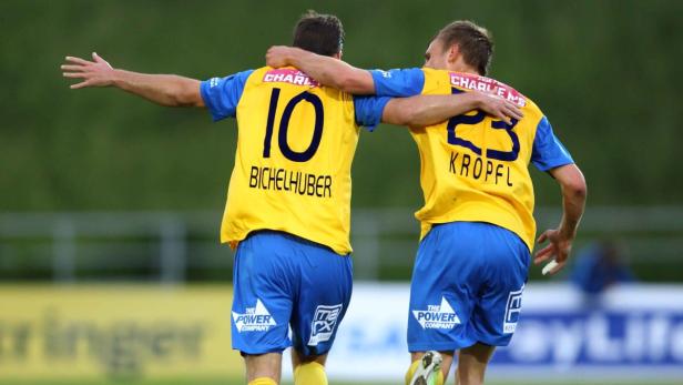 Zwei Fußballspieler in gelb-blauen Trikots umarmen sich, die Rückennummern 10 und 23 sind sichtbar.