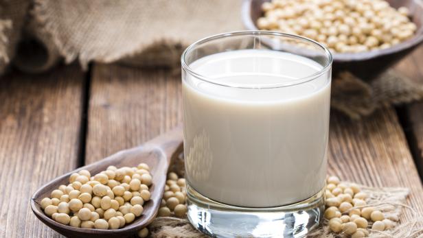 Soy beans on a wooden table with a glass of milk on the side
