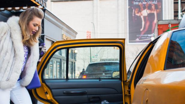 Eine Frau steigt in New York in ein gelbes Taxi.