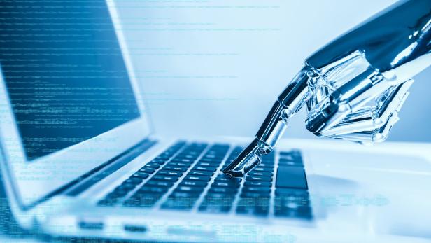 Eine Roboter-Hand tippt auf einer Laptop Tastatur