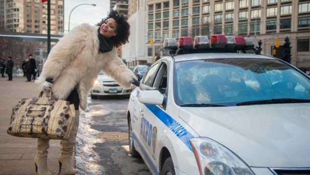 Eine Frau in einem Pelzmantel spricht mit einem Polizisten in einem Streifenwagen in der Stadt.