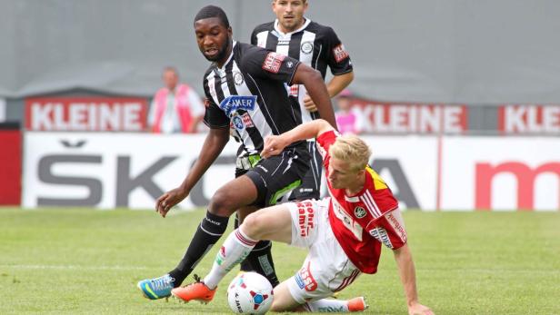 Zwei Fußballspieler kämpfen um den Ball auf dem Spielfeld.