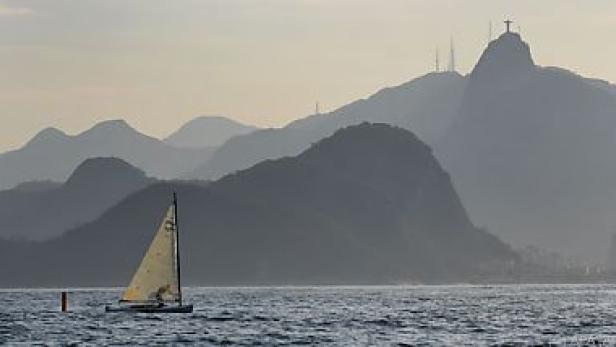 Ein Segelboot fährt vor der Küste von Rio de Janeiro mit dem Zuckerhut im Hintergrund.