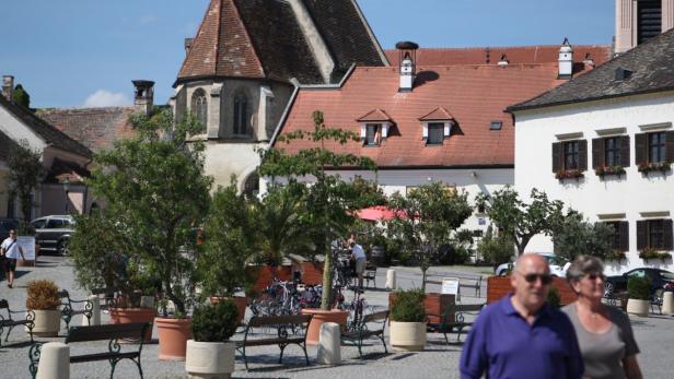 Ein belebter Platz in Rust am Neusiedler See mit historischen Gebäuden und Passanten.