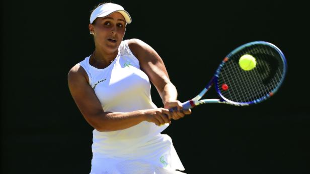 Eine Tennisspielerin schlägt einen Ball mit ihrem Schläger.