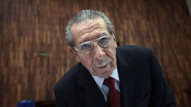 Ein älterer Mann mit Brille, Anzug und Krawatte blickt in die Kamera.