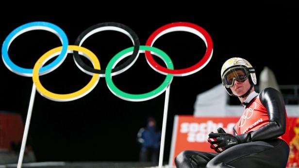 Eine Skispringerin sitzt vor den olympischen Ringen.