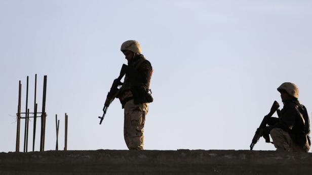 Zwei Soldaten in Uniform und mit Gewehren stehen auf einer Mauer.