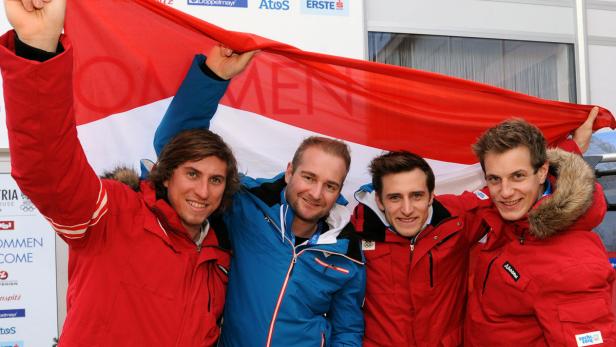 Vier Männer halten eine österreichische Flagge hoch und lächeln.