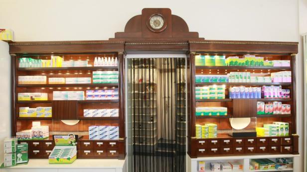 Ein antiker Apothekenschrank mit Medikamenten und einer Uhr darüber.