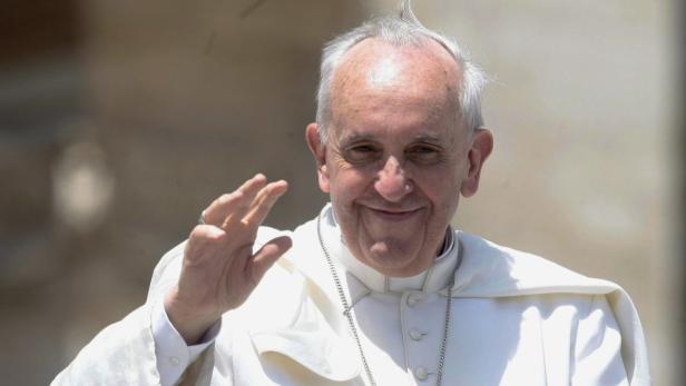 Papst Franziskus lächelt und winkt.
