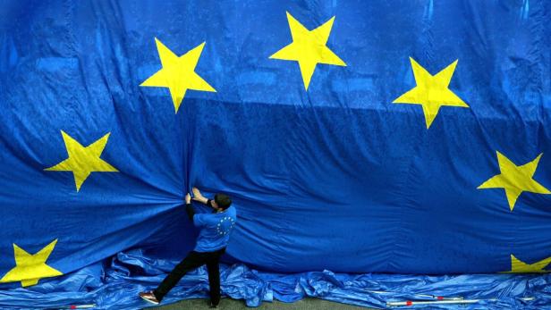 Eine Person drapiert eine große Flagge der Europäischen Union.