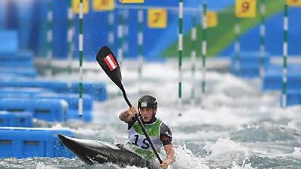 Ein Kanuslalomfahrer mit österreichischem Paddel kämpft sich durch das Wildwasser.