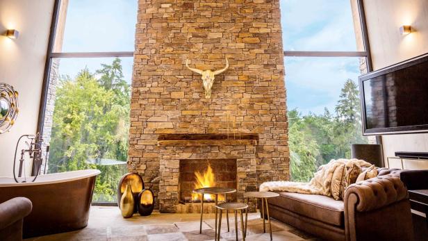 Ein luxuriöses Wohnzimmer mit Kamin, Geweih und Blick auf den Wald.