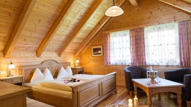 Ein romantisch dekoriertes Schlafzimmer mit Holzwänden und einem Doppelbett mit Rosen.