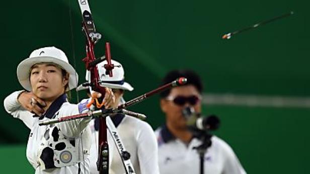 Eine Bogenschützin zielt mit Pfeil und Bogen auf ein Ziel.