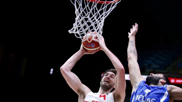 Ein Basketballspieler wirft den Ball in den Korb, während ein Gegenspieler versucht, ihn zu blocken.