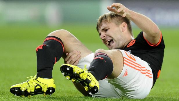 Ein Fußballspieler liegt verletzt auf dem Rasen und hält sich das Bein.