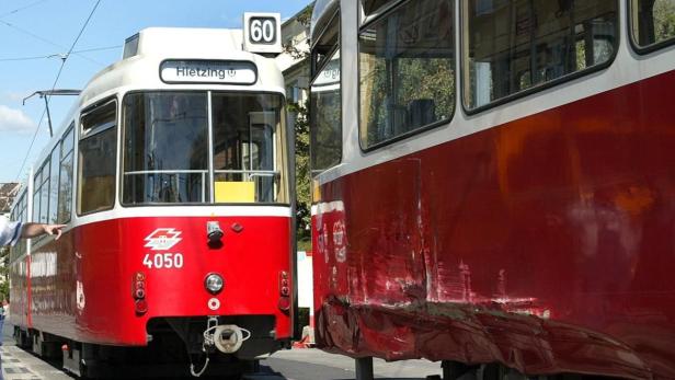 Zwei rote und weiße Straßenbahnen in Wien, eine mit der Nummer 60 und dem Ziel Hietzing.
