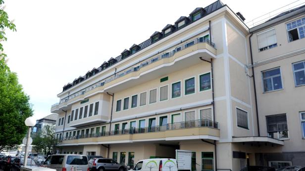 Ein mehrstöckiges Gebäude mit hellgelber Fassade und grünen Fensterrahmen.